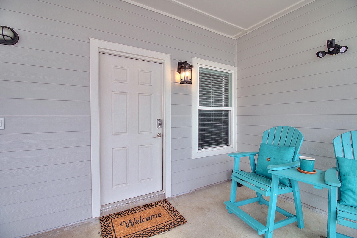 Your charming covered porch welcomes you with bright turquoise chairs and coastal charm—perfect for morning coffee or evening conversations.