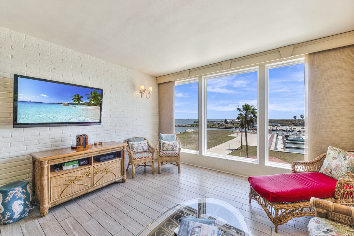 Unwind in your bright living room with stunning marina views and tropical TV backdrop for perfect relaxation.