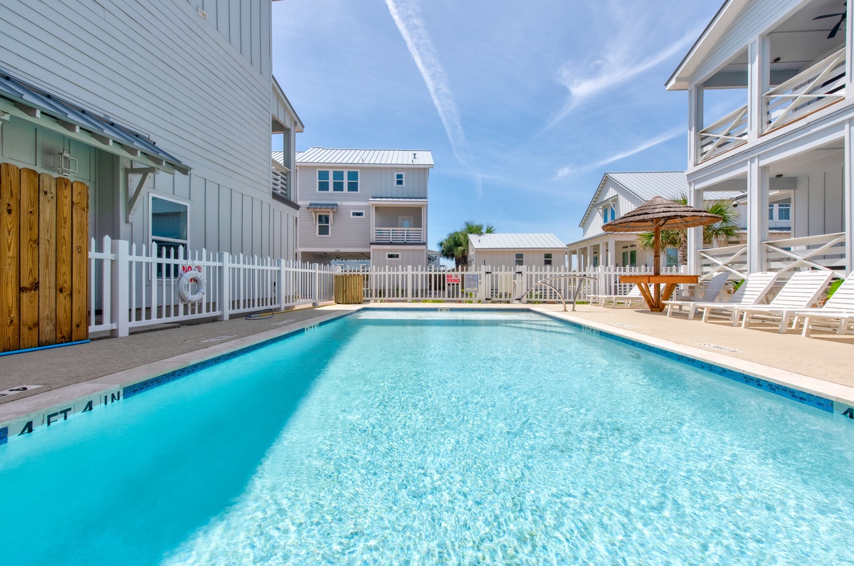 Dive into crystal-clear waters in your community pool oasis, surrounded by coastal charm and endless blue skies above.