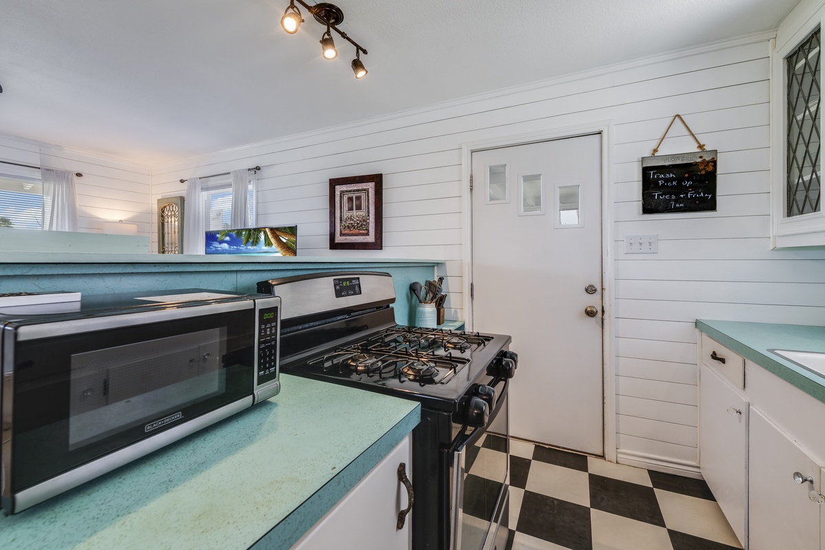 Step into your fully equipped kitchen featuring charming turquoise countertops, modern appliances, and classic checkerboard flooring. Whip up your favorite meals with ease in this bright, welcoming space.