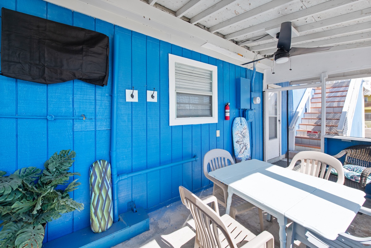 Enjoy meals and morning coffee in your covered outdoor dining area with ocean-blue walls and tropical decor.