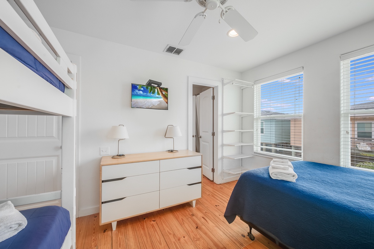 Your bright bedroom offers peaceful rest with comfy beds, coastal artwork, and warm hardwood floors beneath your feet.