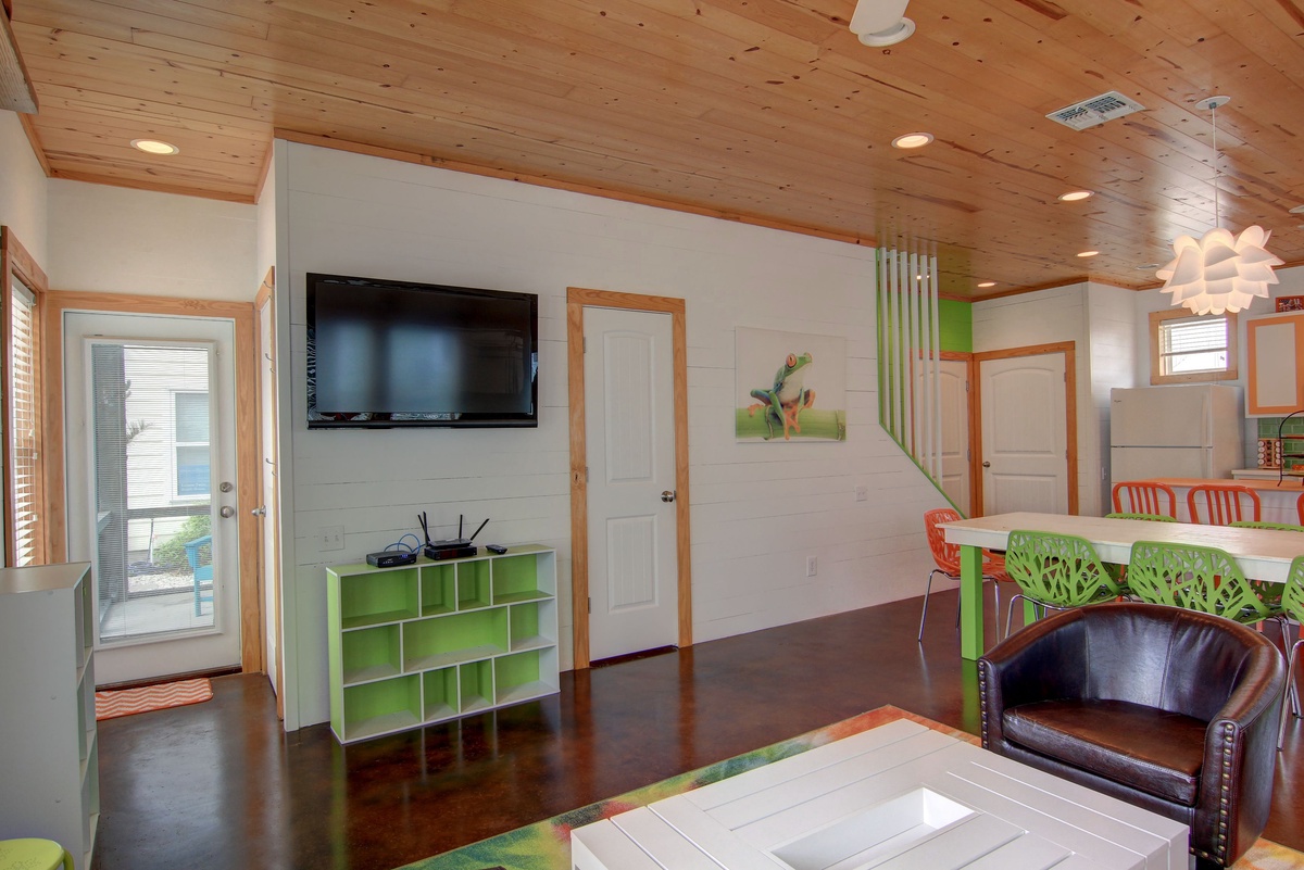 Relax in your bright living space with wood beam ceilings, flat-screen TV, and colorful modern furniture for comfortable indoor moments.