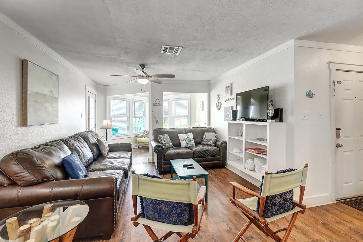 Sink into comfortable leather sofas in your bright, airy living room where coastal charm meets modern comfort for perfect relaxation.