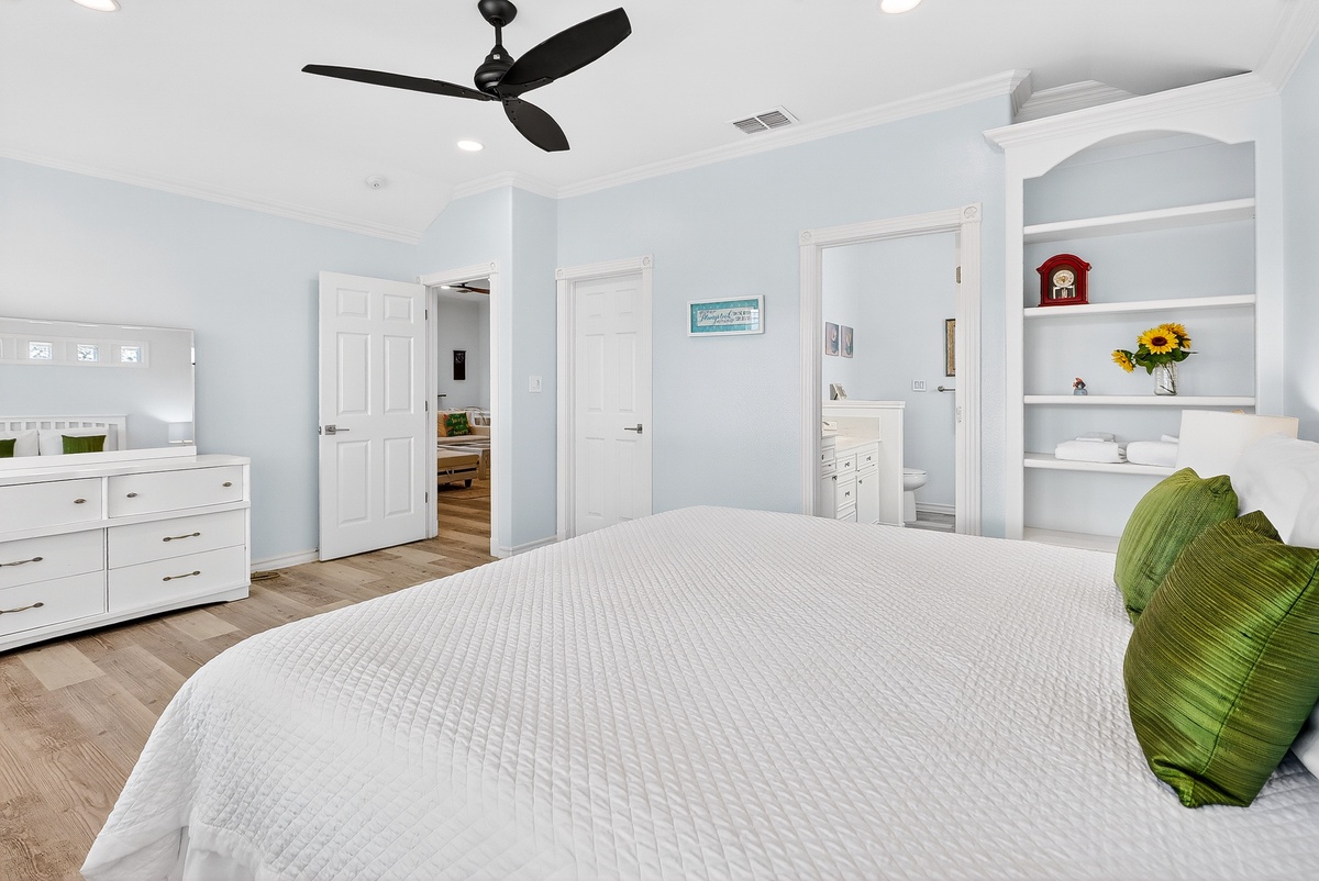 Drift off to sleep in this serene bedroom, where soft blue walls and a ceiling fan create your perfect retreat.