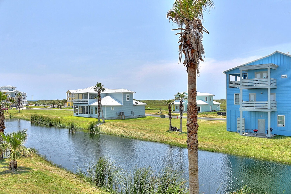 Coastal vacation homes feature colorful architecture overlooking peaceful waterways with palm trees and expansive green spaces.