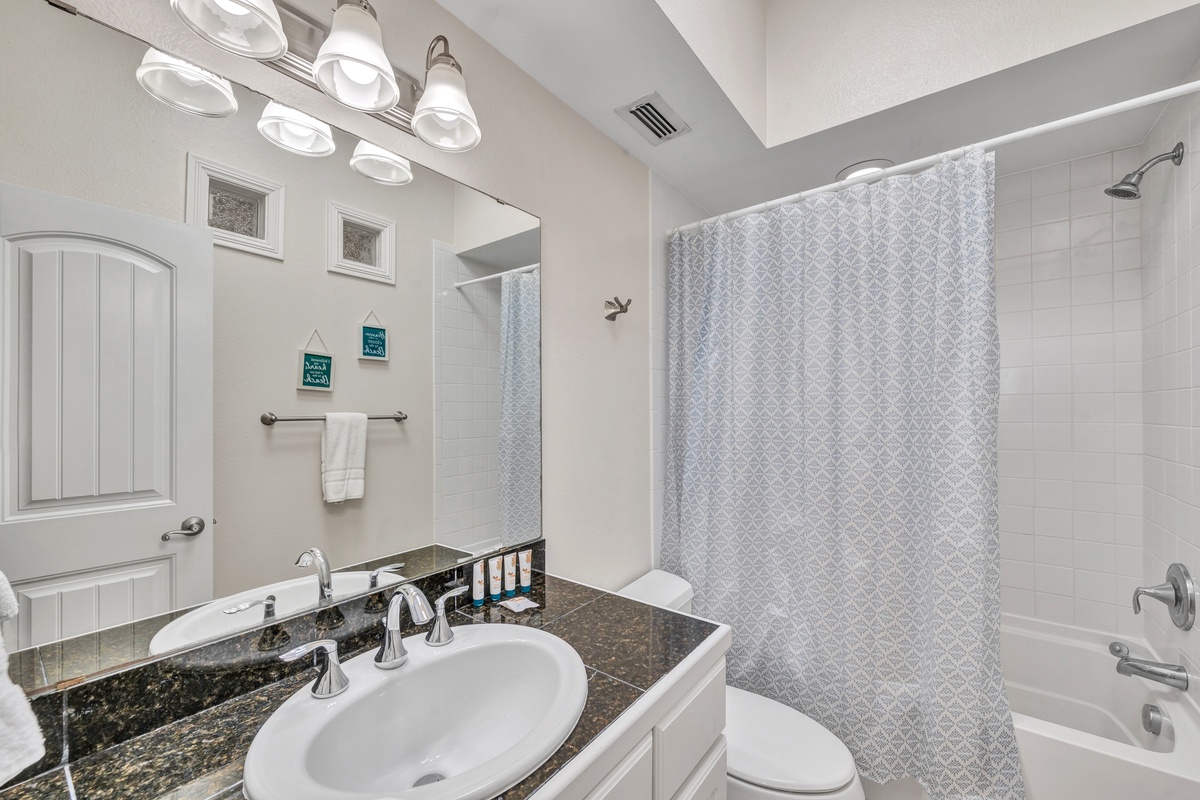 Refresh in your pristine bathroom with elegant granite countertops, bright vanity lighting, and a spacious tub-shower combo.