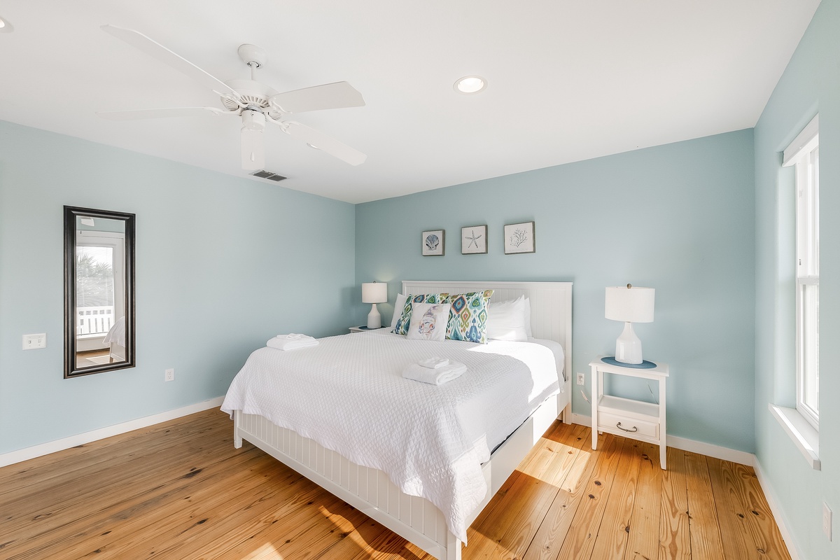 Drift off to peaceful dreams in this serene coastal bedroom with soft seafoam walls and warm hardwood floors.