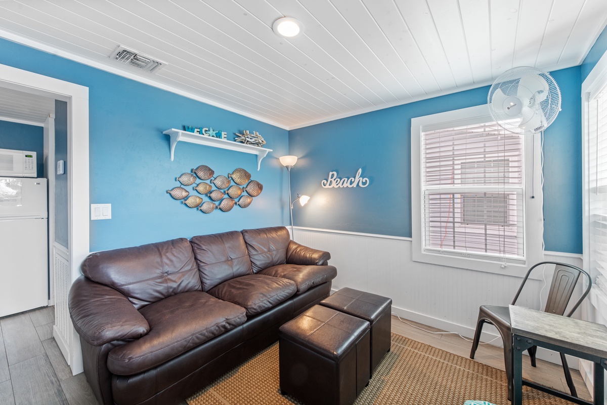Sink into plush leather seating in your beach-themed living space, where ocean-blue walls and coastal decor create the perfect spot to unwind.