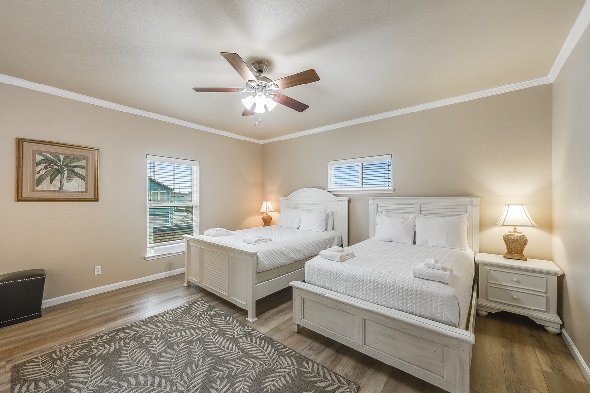 Relax in your peaceful bedroom featuring two comfortable beds, crisp linens, and tropical artwork that sets the perfect vacation mood.