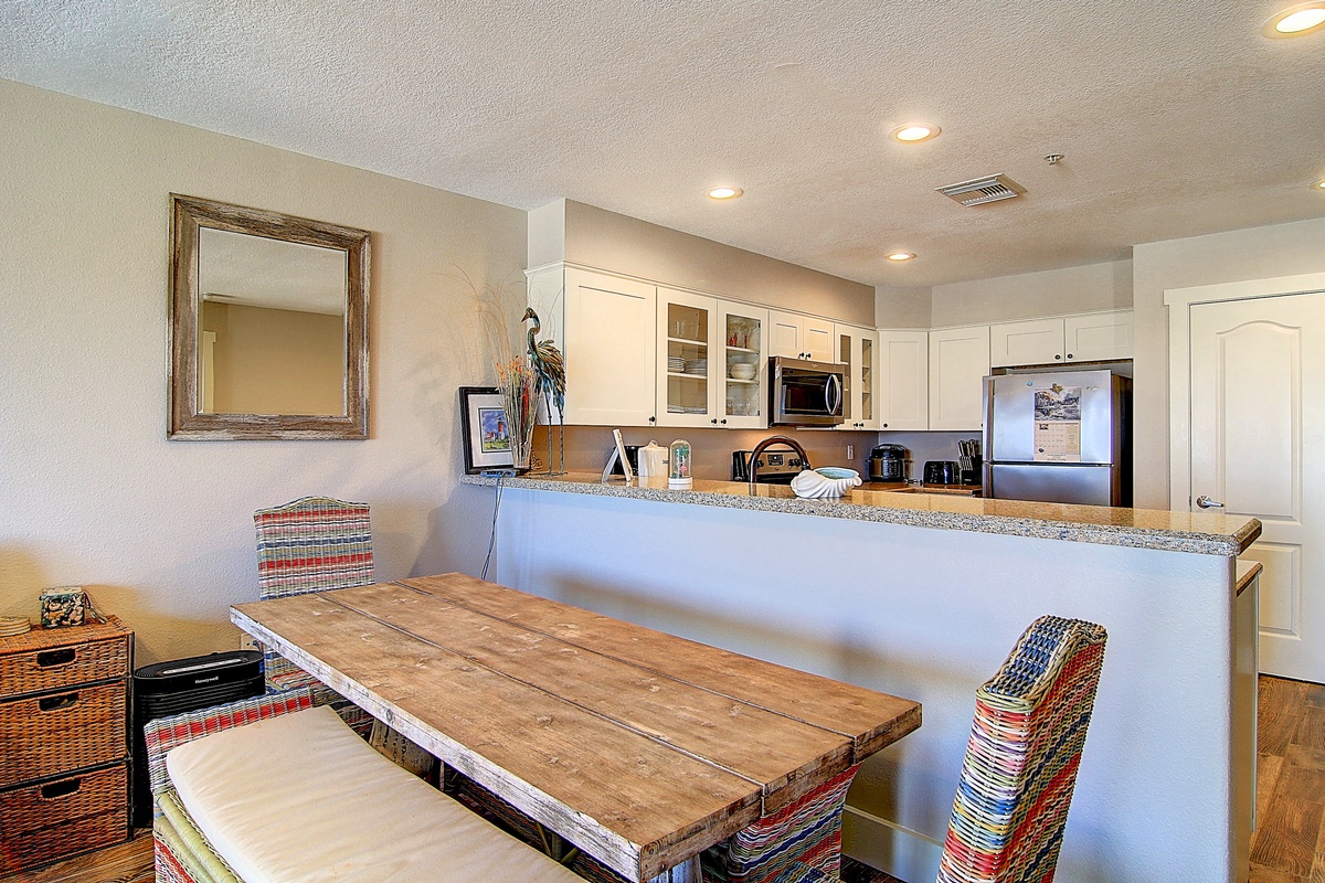Your open kitchen and dining area blend seamlessly, with granite countertops and colorful woven chairs creating a warm, welcoming space for meals.