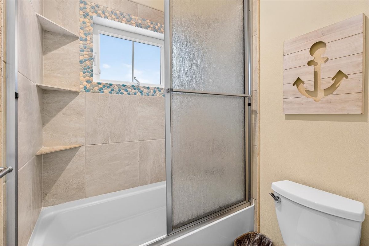 Relax in your coastal-themed bathroom featuring ocean-inspired mosaic tiles and charming nautical touches that make every soak feel like a seaside escape.
