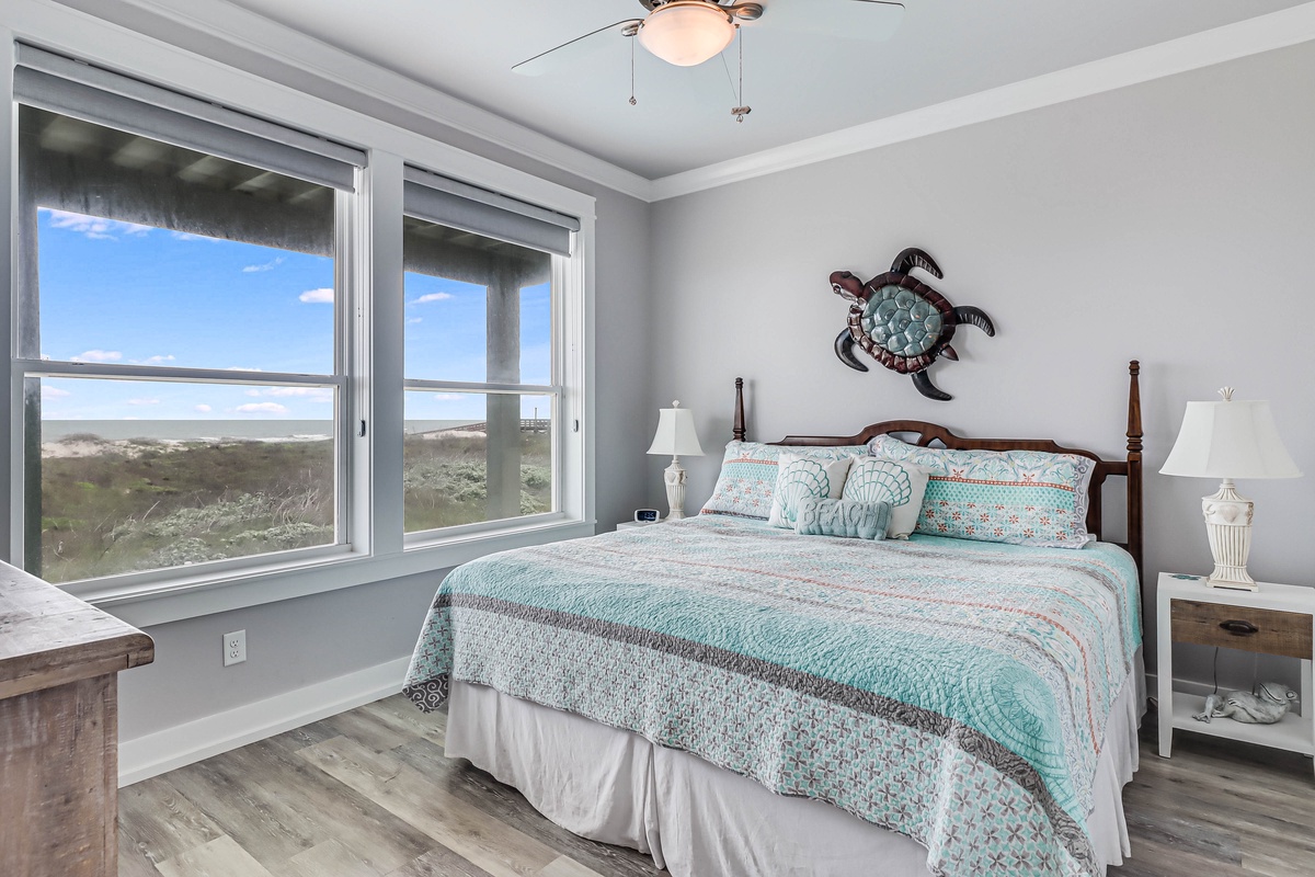 Wake up to stunning natural landscapes through your bedroom's expansive windows, where coastal-themed decor creates a serene retreat.