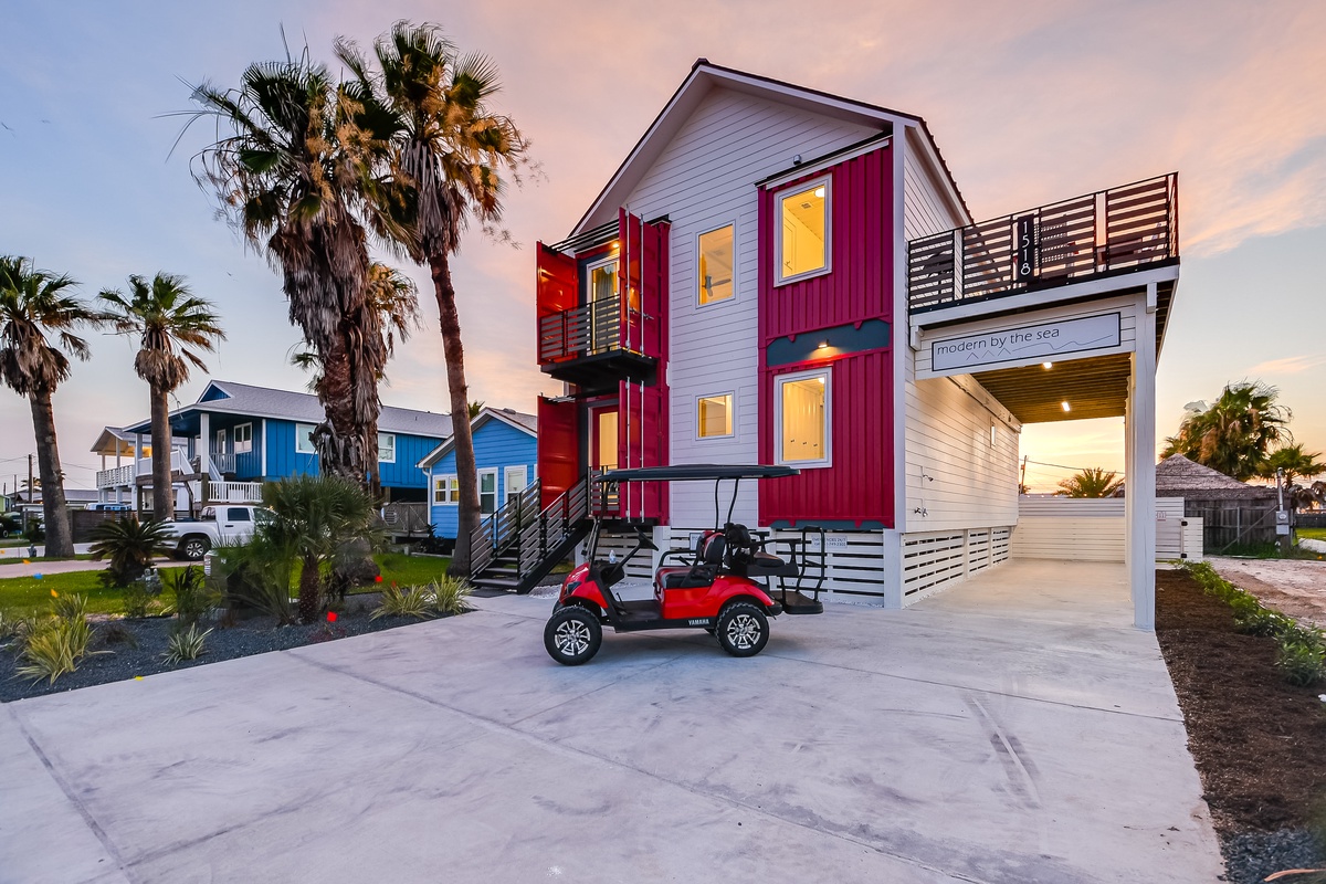 Modern coastal retreat with tropical palms and convenient golf cart parking at arrival.