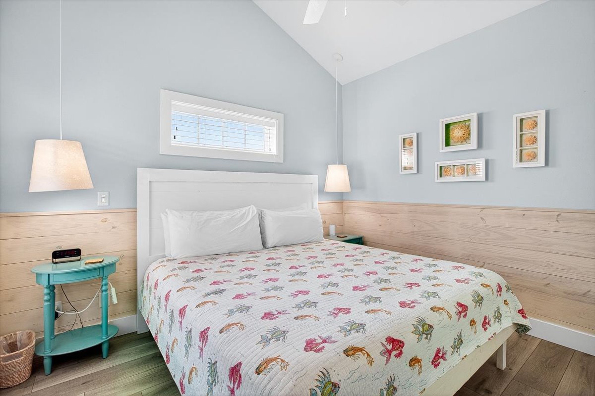 Rest peacefully in your serene bedroom featuring soft blue walls, warm wood accents, and charming coastal bedding that invites sweet dreams.