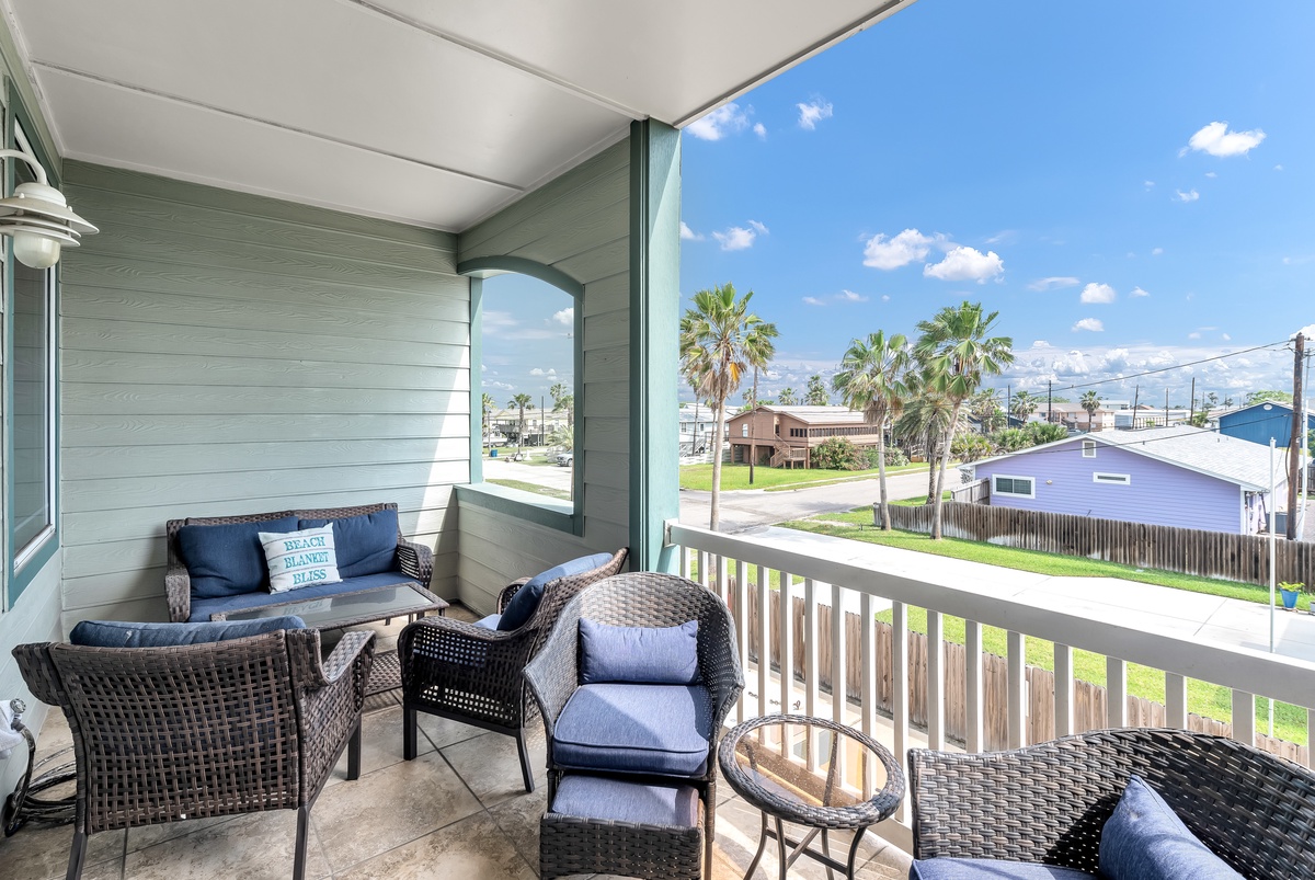 Relax on this covered balcony with comfortable seating while enjoying coastal breezes and neighborhood views.