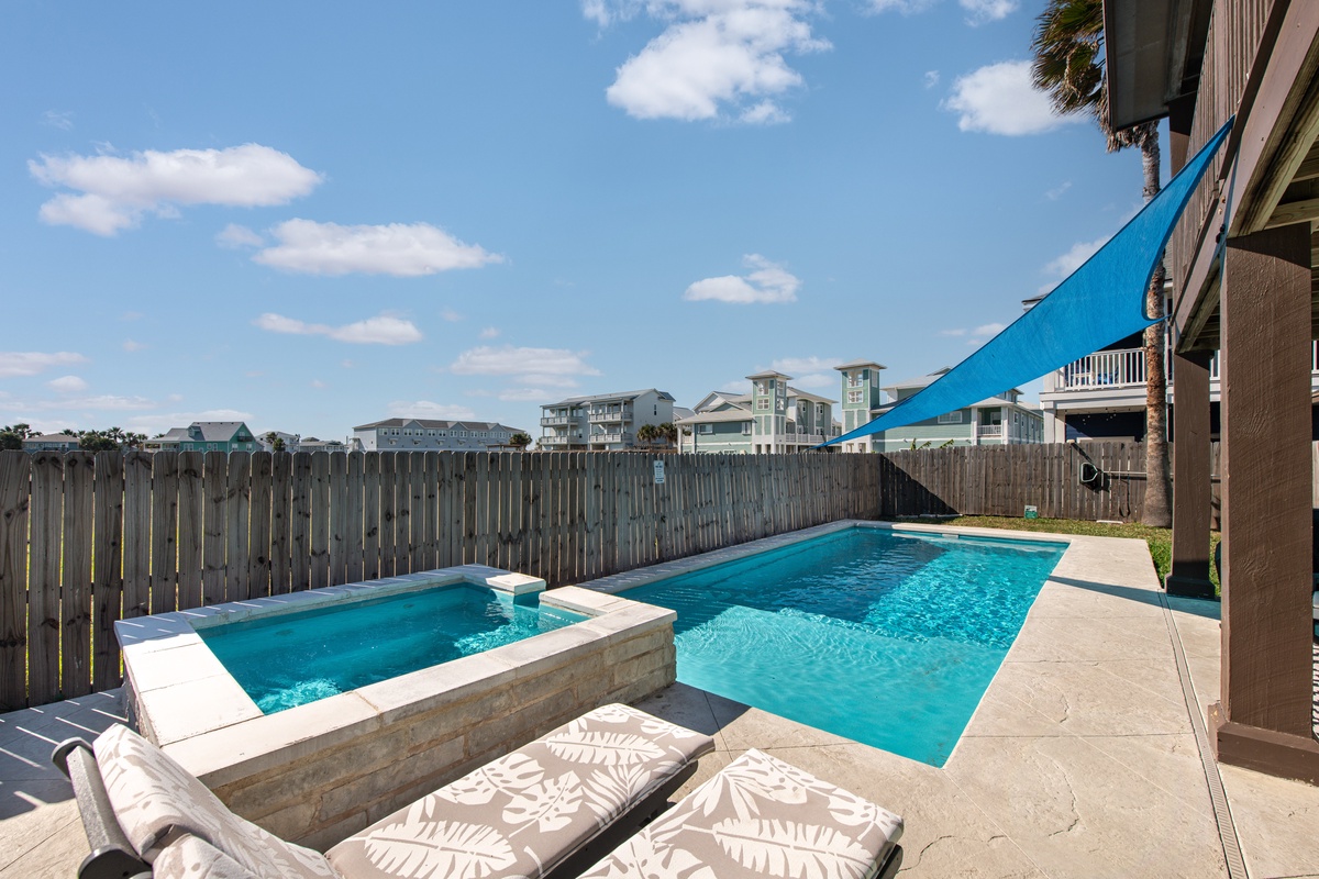 Dive into your private pool paradise with sparkling waters, hot tub, and comfortable loungers under a cheerful blue shade sail.