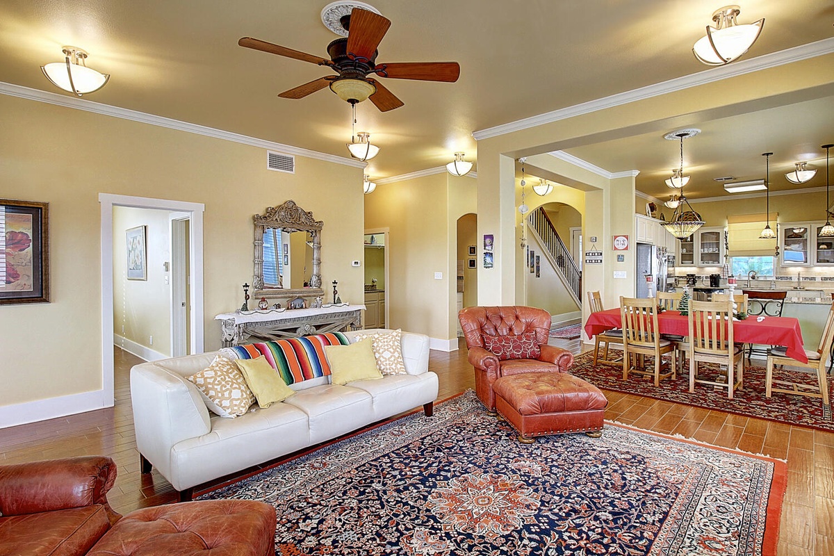 Relax in your spacious living room featuring a plush sofa, leather armchairs, and an ornate rug that creates the perfect gathering space.