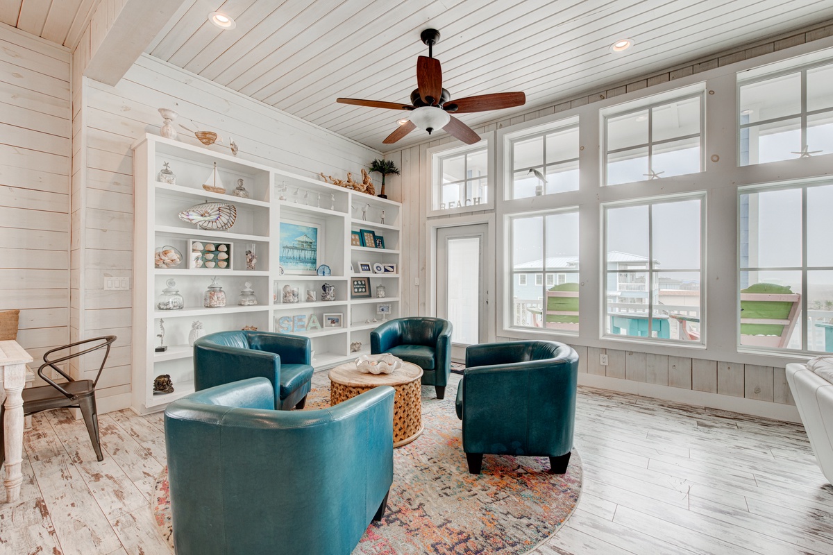 Relax in your bright living room with turquoise armchairs and built-in shelving, where coastal charm meets comfortable conversation.