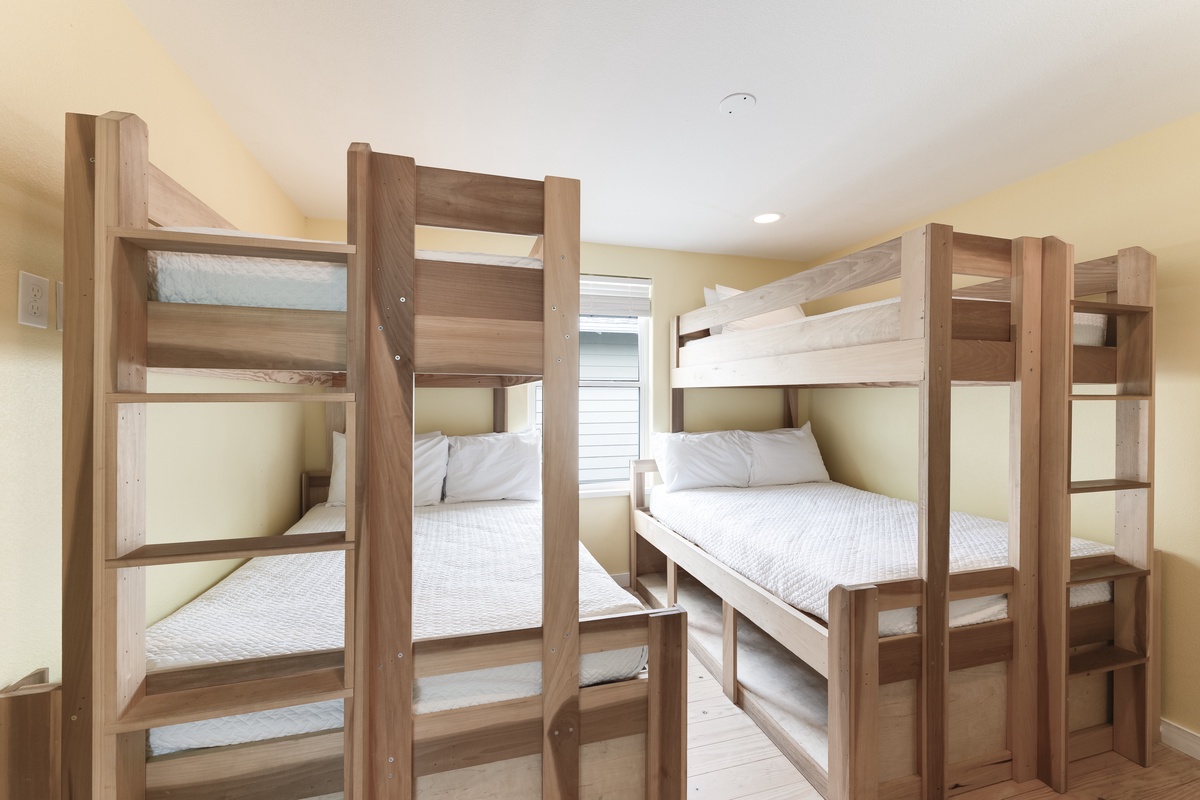 Your group will love this cozy bunk room with sturdy wooden beds and crisp white linens—perfect for kids or friends sharing adventures together.