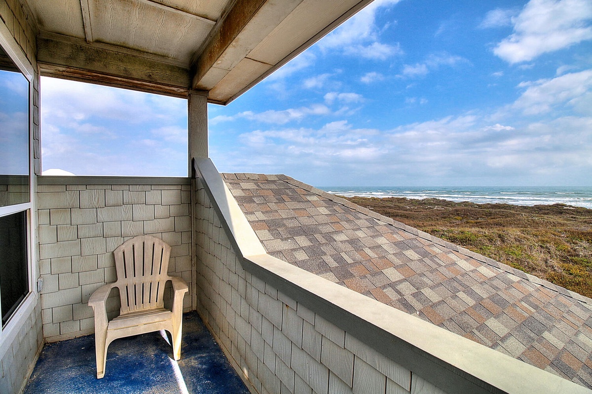 Relax on your private balcony while ocean waves roll endlessly beyond coastal vegetation.