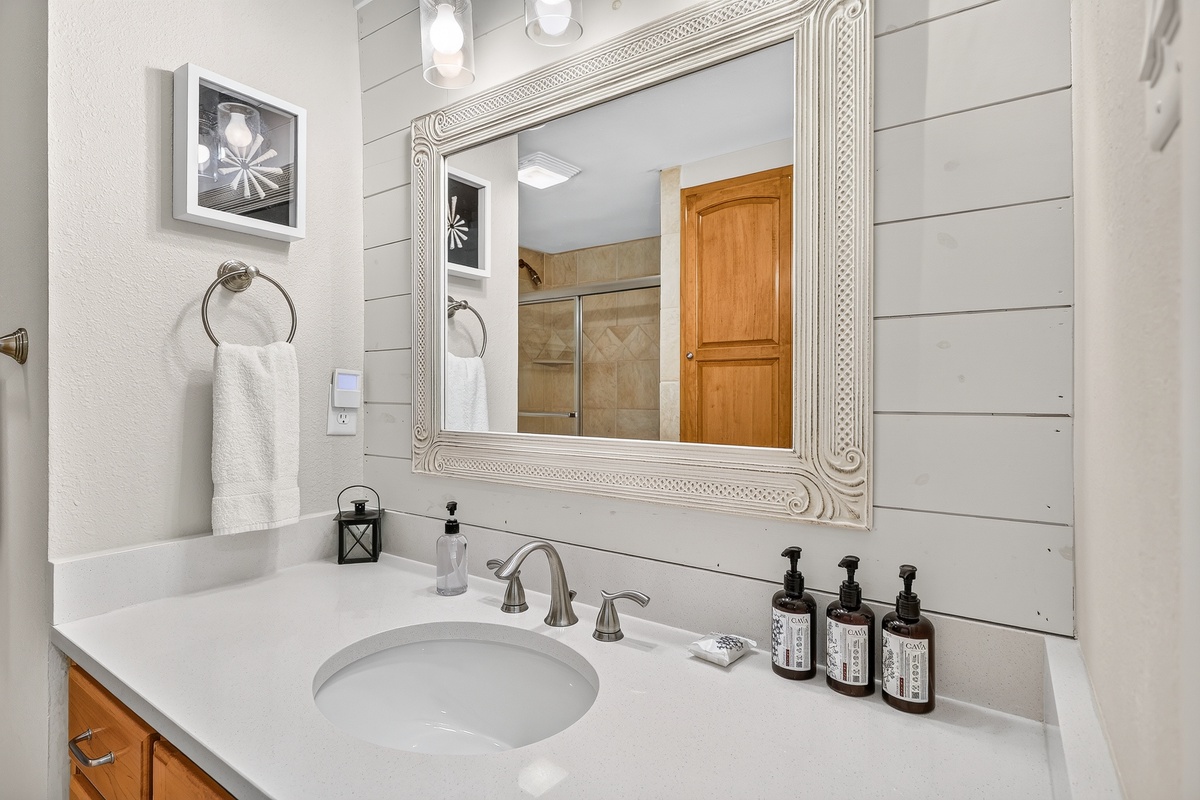 Freshen up in your bright, spotless bathroom with its spacious vanity, elegant fixtures, and plush towels. The charming shiplap walls and warm wood accents create a welcoming retreat.