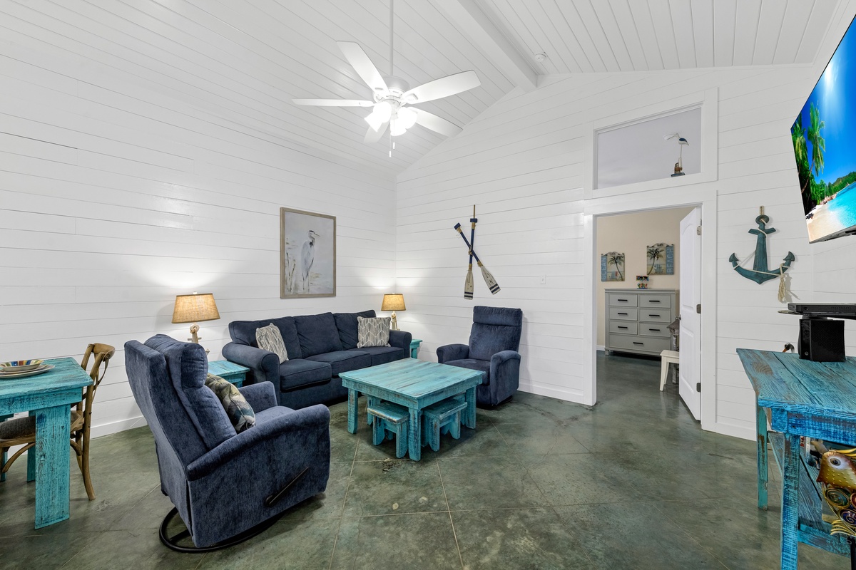 Relax in your coastal-themed living room with plush navy seating, rustic turquoise accents, and nautical charm throughout.