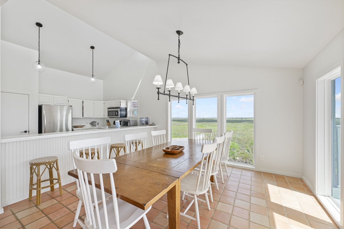 Your bright kitchen flows seamlessly into the dining area, where you'll gather around the rustic farmhouse table while panoramic windows frame endless countryside views.