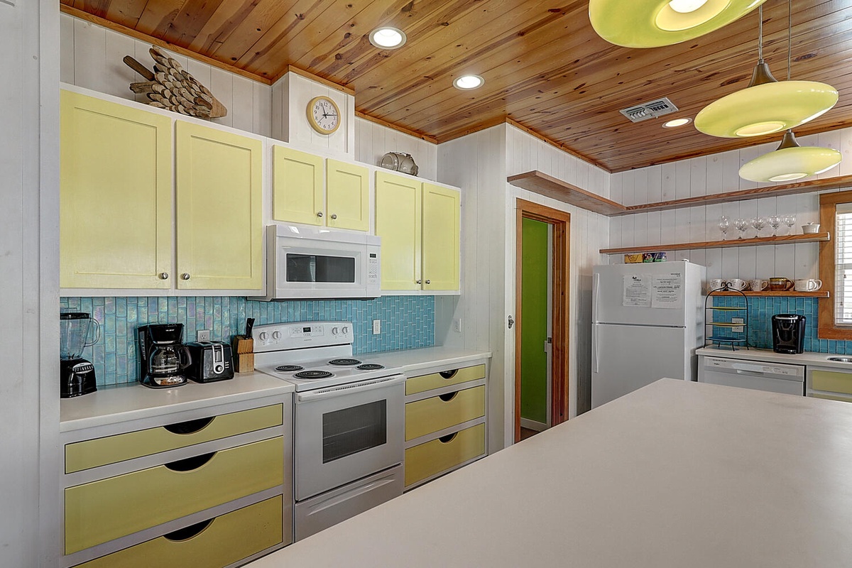 Your fully-equipped kitchen features cheerful lime green cabinets, modern appliances, and a spacious island perfect for preparing memorable meals together.