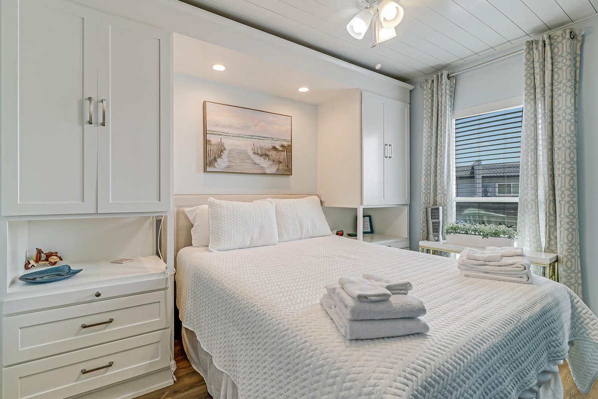 Rest in your cozy bedroom with built-in storage, soft linens, and peaceful views through patterned curtains.