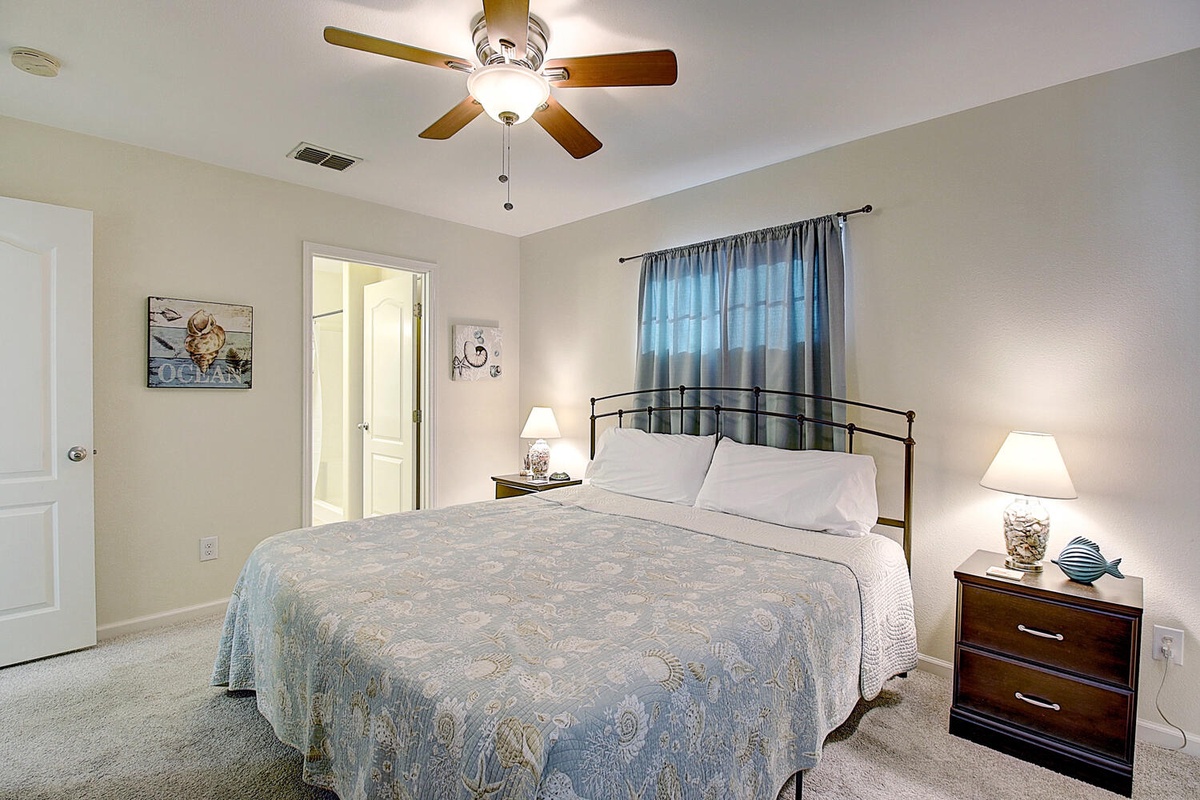 Your peaceful bedroom features a ceiling fan, soft lighting, and ocean-inspired decor to help you unwind after beach adventures.