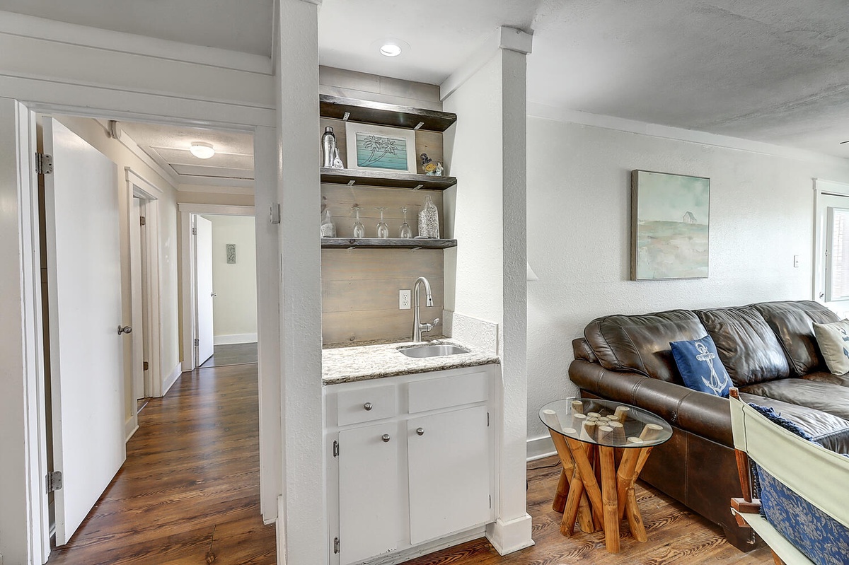 Relax on the plush leather sofa while enjoying your private wet bar with granite counters and coastal artwork.