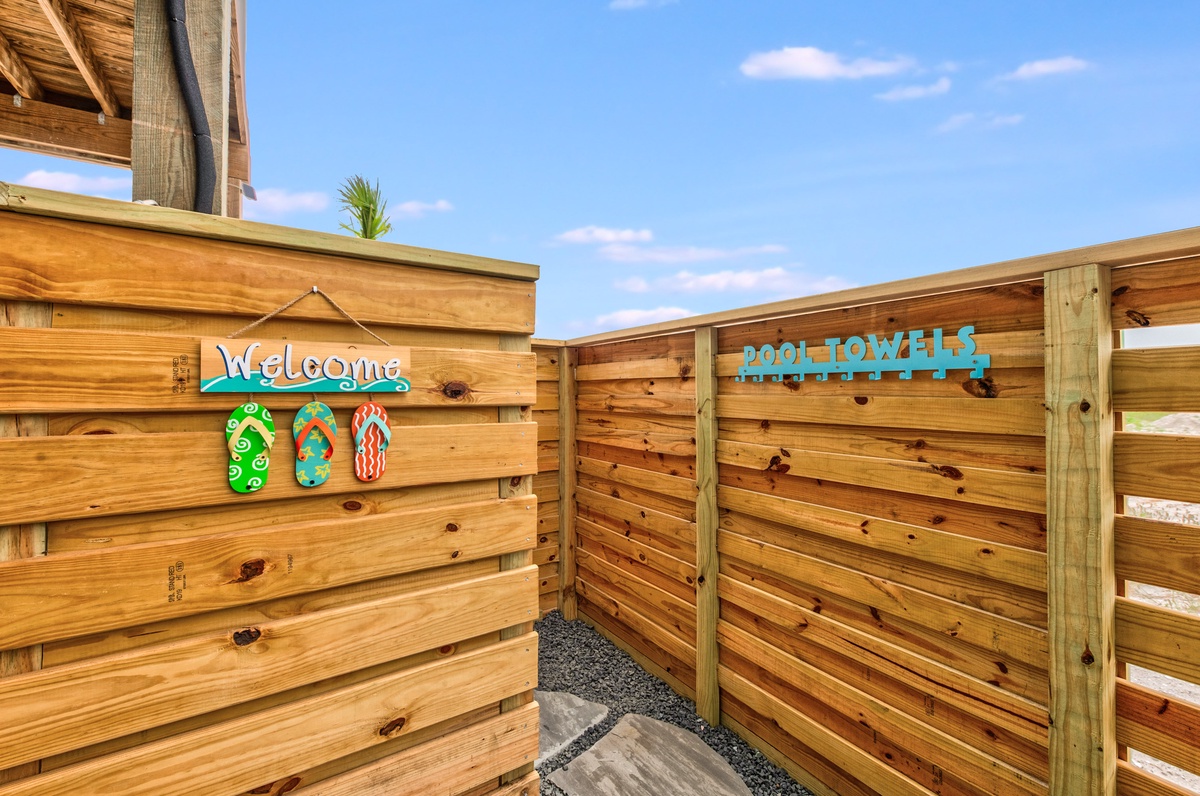 Welcome signage and pool towel station mark the entrance to this beachside property's outdoor amenities.