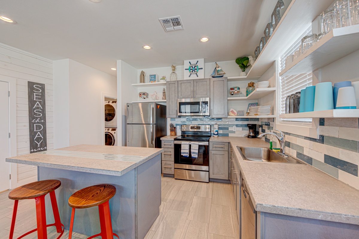 Cook up coastal memories in this fully equipped kitchen with modern appliances, beach-themed décor, and a breakfast bar perfect for morning coffee.