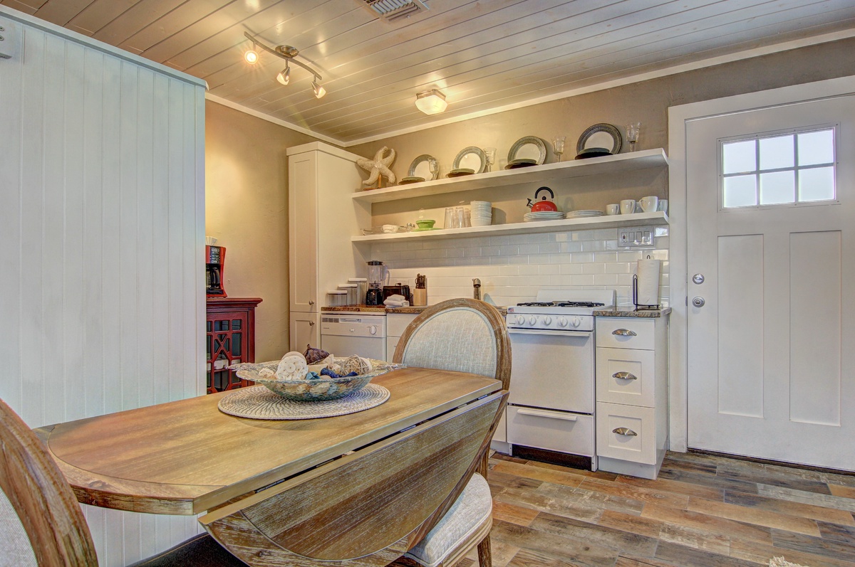 Step into your charming cottage kitchen where rustic wood floors meet vintage appliances and open shelving displays local pottery for your morning coffee ritual.