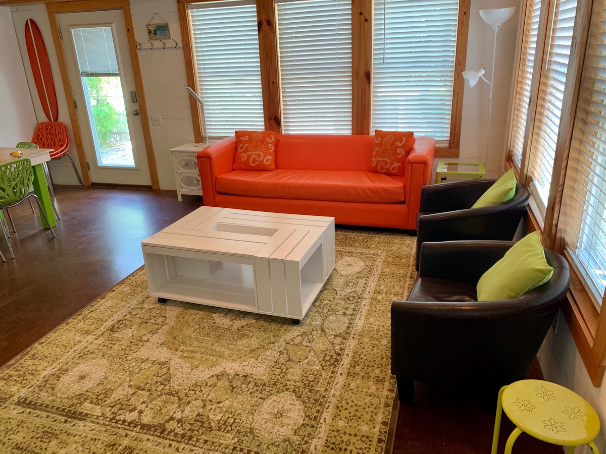 Sink into vibrant orange comfort in your open living space, where warm wood tones and colorful accents create the perfect retreat.