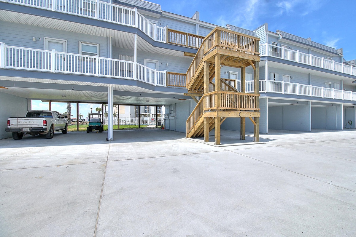 Covered parking and wooden staircase provide convenient access to upper floors at this waterfront property.