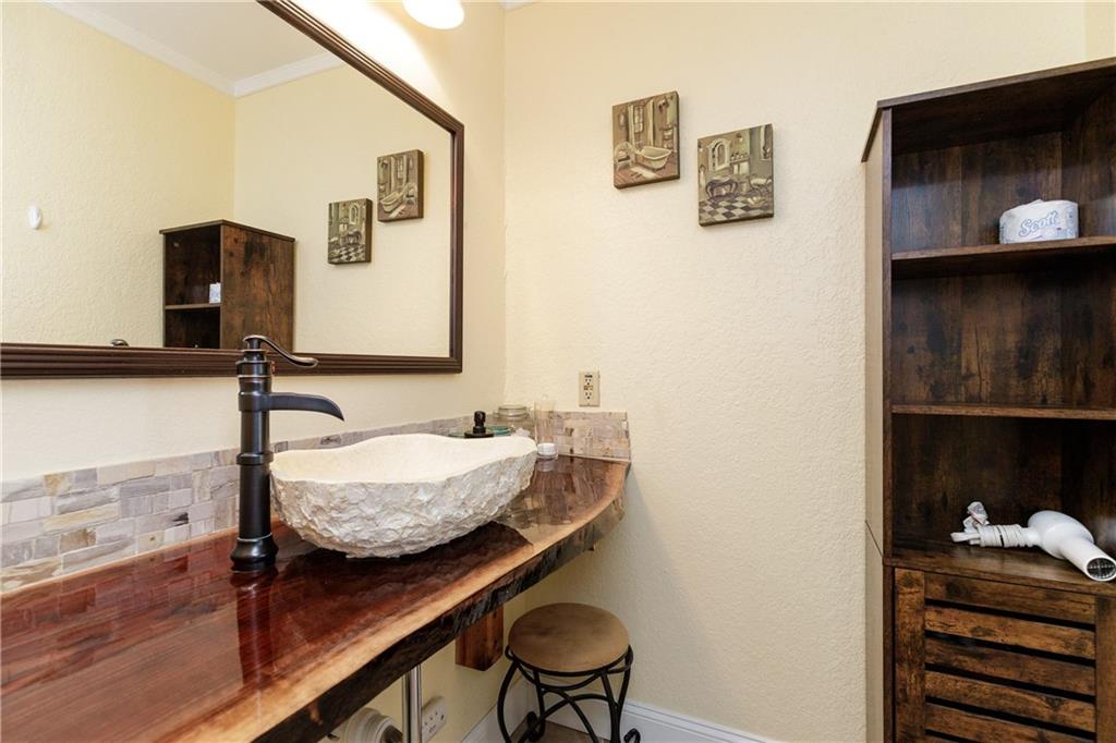 Unwind in your beautifully crafted bathroom featuring warm wood finishes, a stunning stone vessel sink, and thoughtful artistic touches that create a spa-like retreat.
