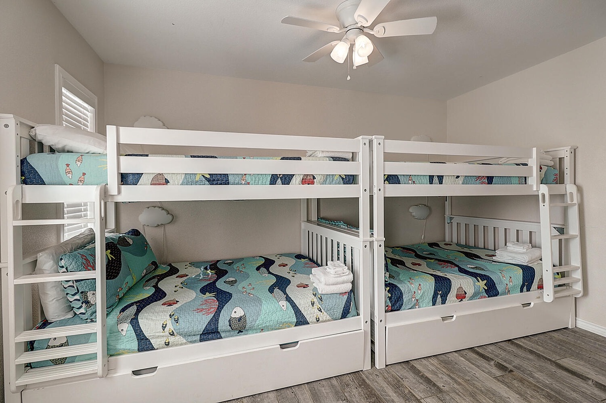 Your kids will love this cozy bunk room with whimsical ocean-themed bedding and a ceiling fan for comfort.