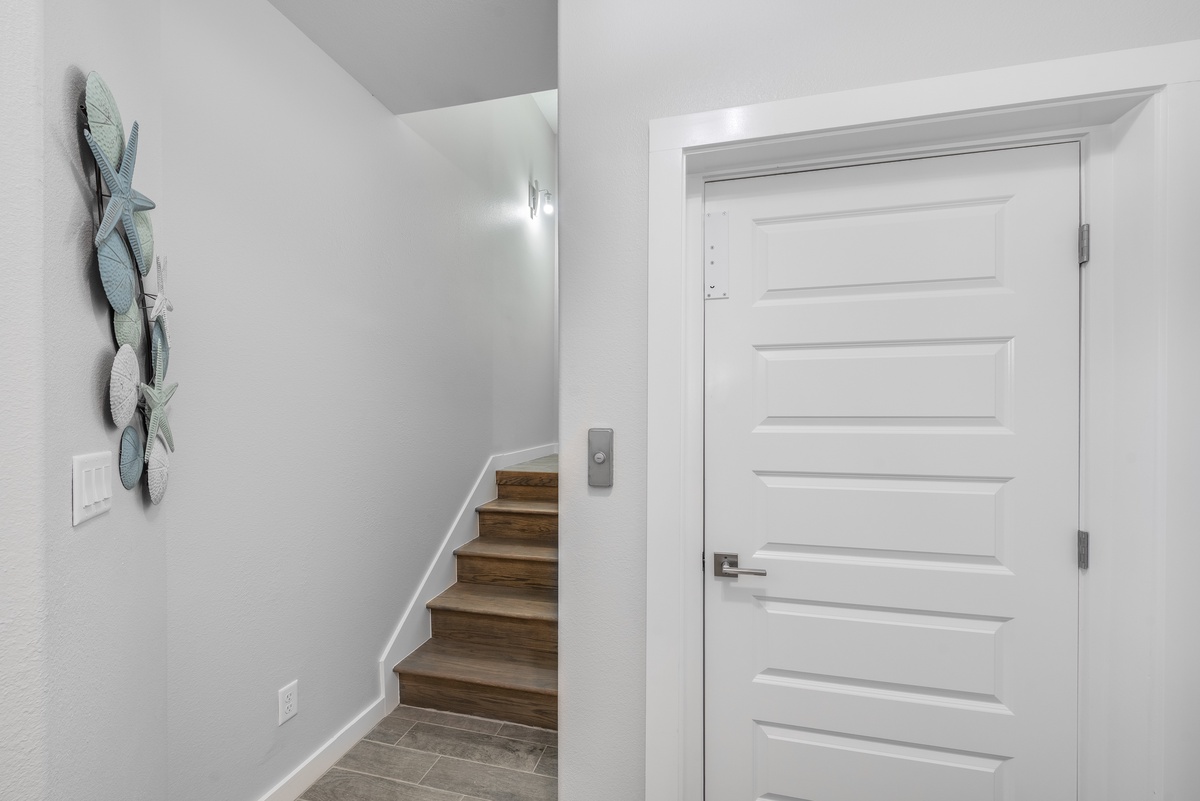 Stylish modern entryway welcomes you with clean lines and coastal-inspired wall art, leading to your comfortable spaces upstairs.
