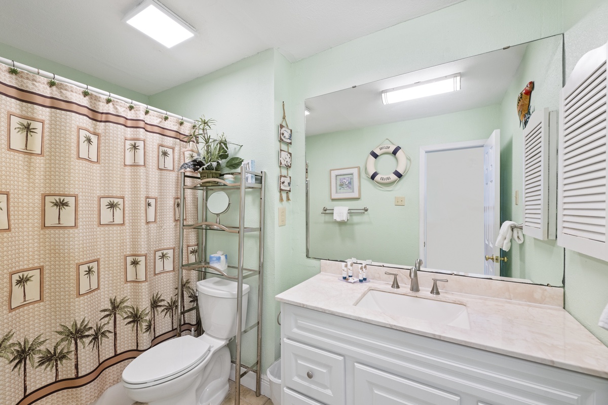Refresh in your charming coastal bathroom featuring tropical palm accents and soothing mint walls that create a peaceful beachside retreat.