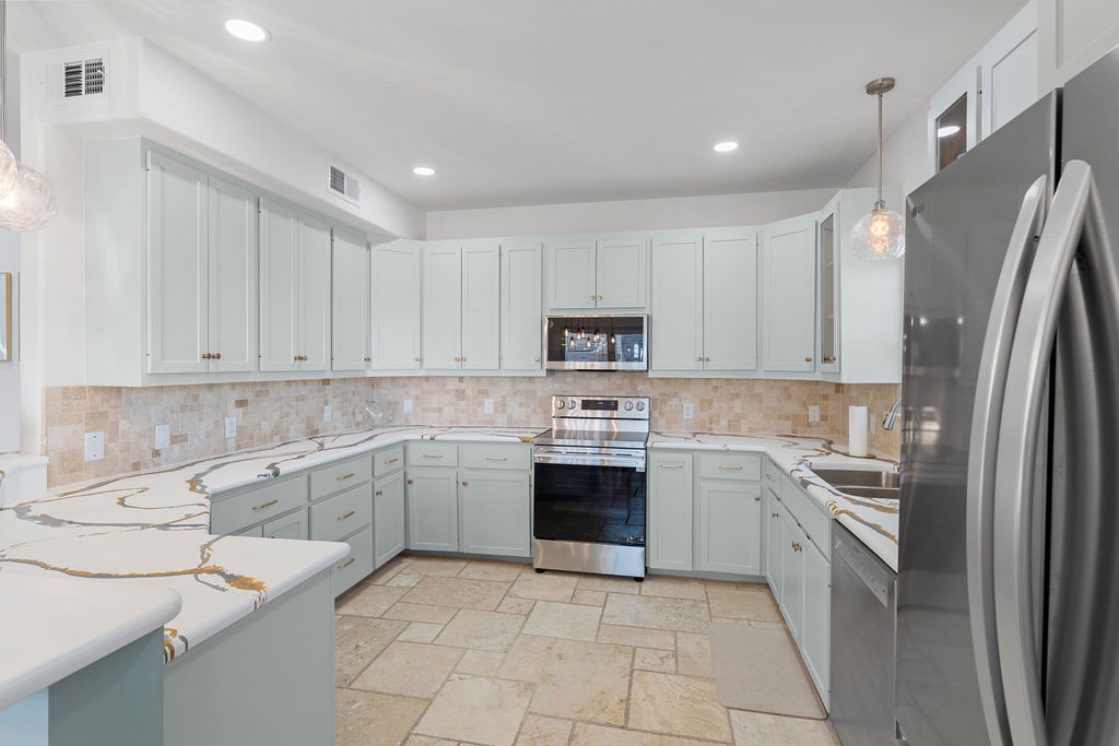 Your spacious modern kitchen features elegant marble countertops, stainless steel appliances, and soft blue cabinetry creating a serene cooking experience.