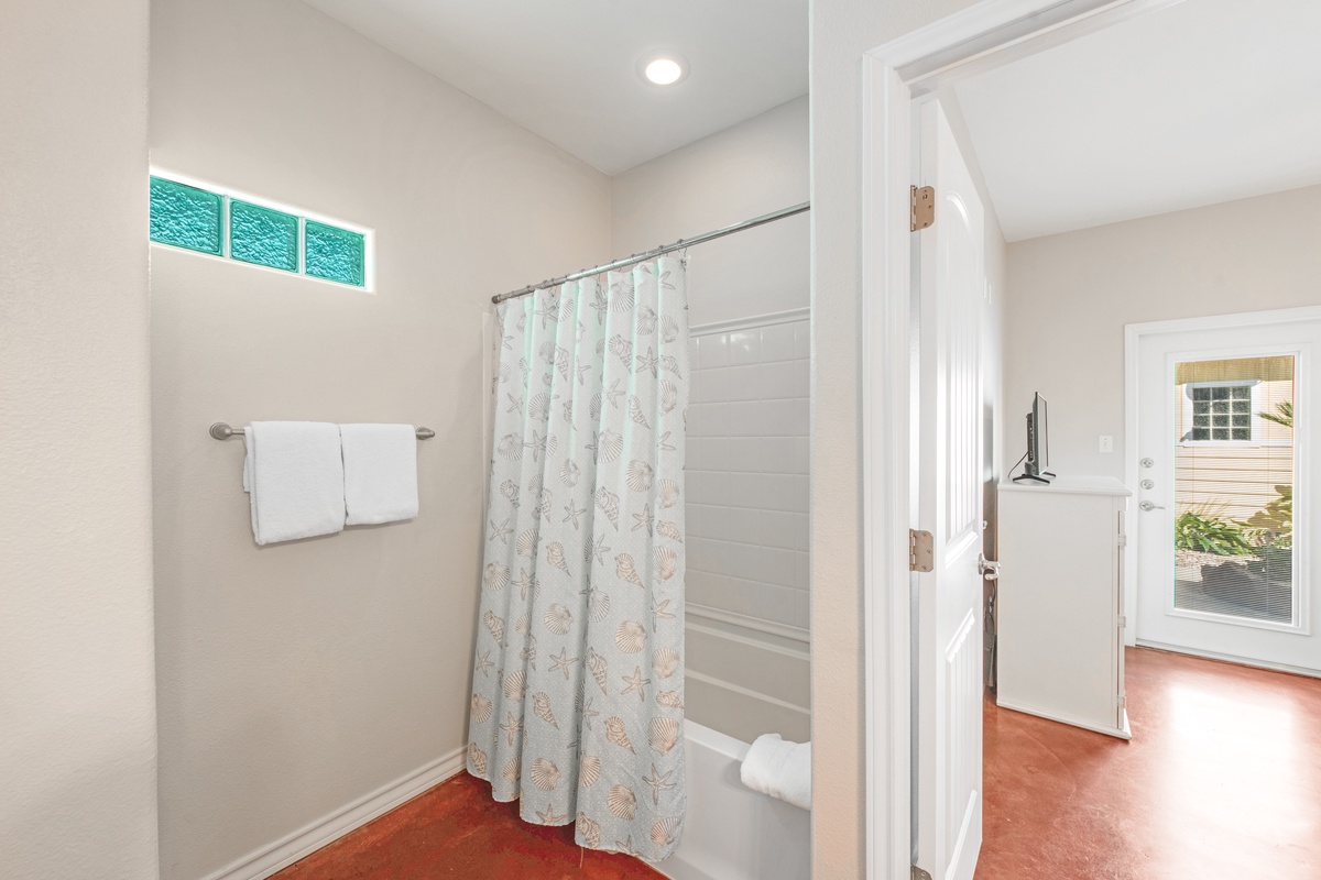 Step into your bright, clean bathroom featuring a relaxing tub-shower combo with coastal-themed curtains and natural light.