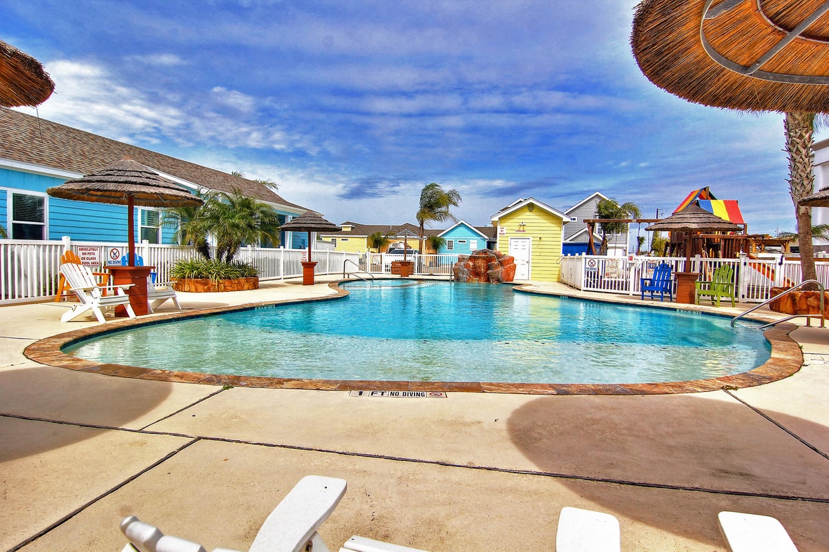 Dive into your tropical escape with this sparkling pool surrounded by vibrant beach cottages and swaying palms.