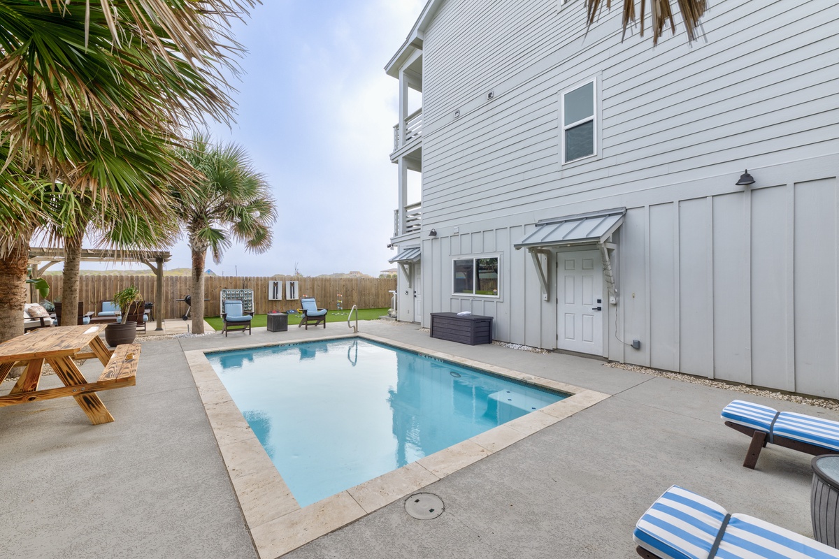 Your private pool awaits surrounded by tropical palms, with comfortable lounge chairs for soaking up the coastal sunshine.