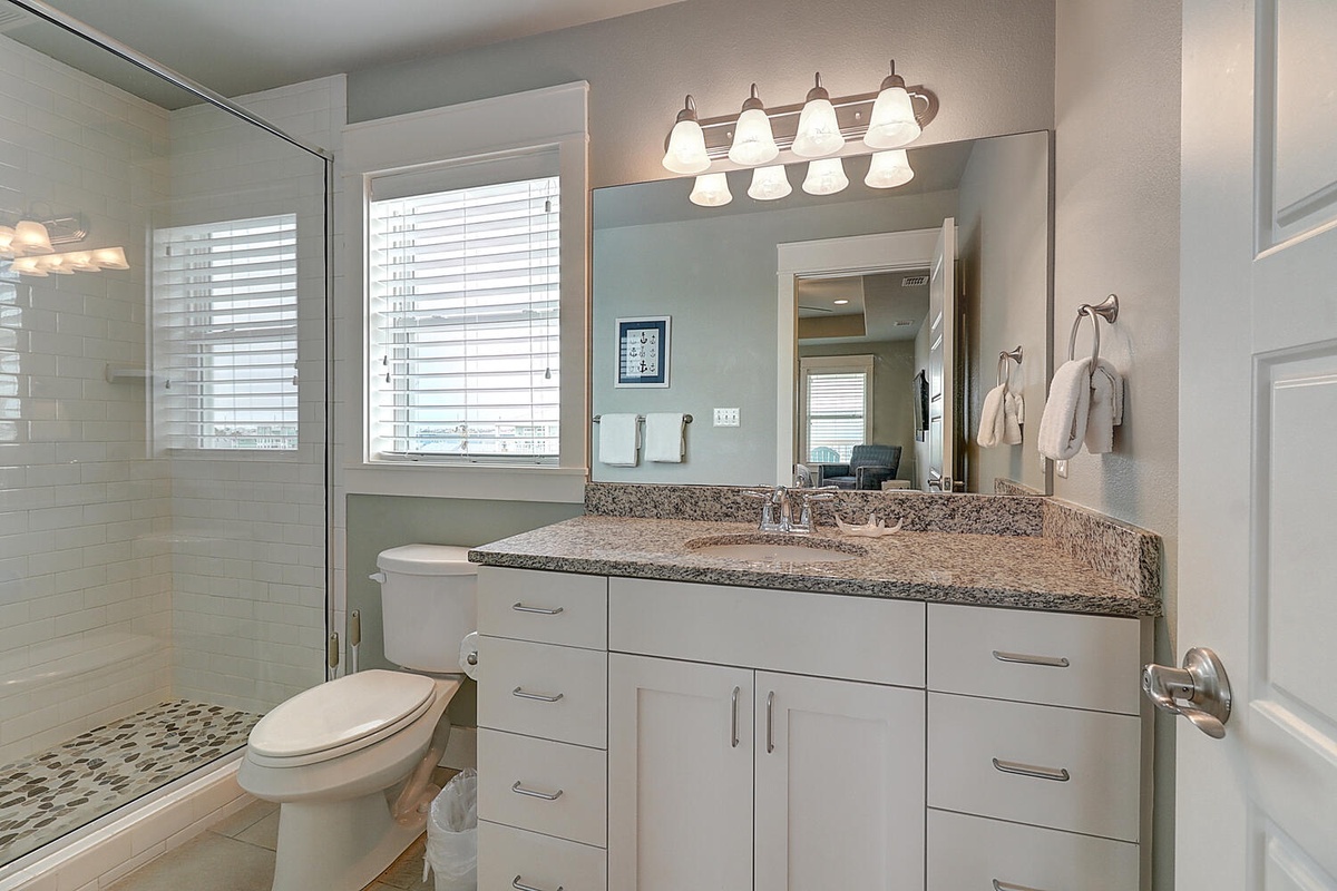 Pamper yourself in this spa-like bathroom featuring granite countertops, elegant lighting, and a spacious walk-in shower with beautiful tile work.
