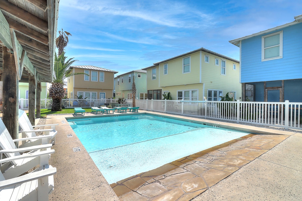 Dive into your private oasis with crystal-clear pool waters surrounded by colorful coastal homes and swaying palms.