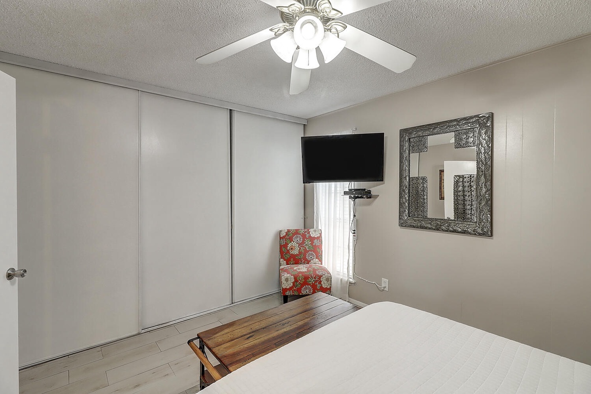 Relax in your comfortable bedroom with modern amenities, ceiling fan, flat-screen TV, and elegant furnishings for a restful stay.
