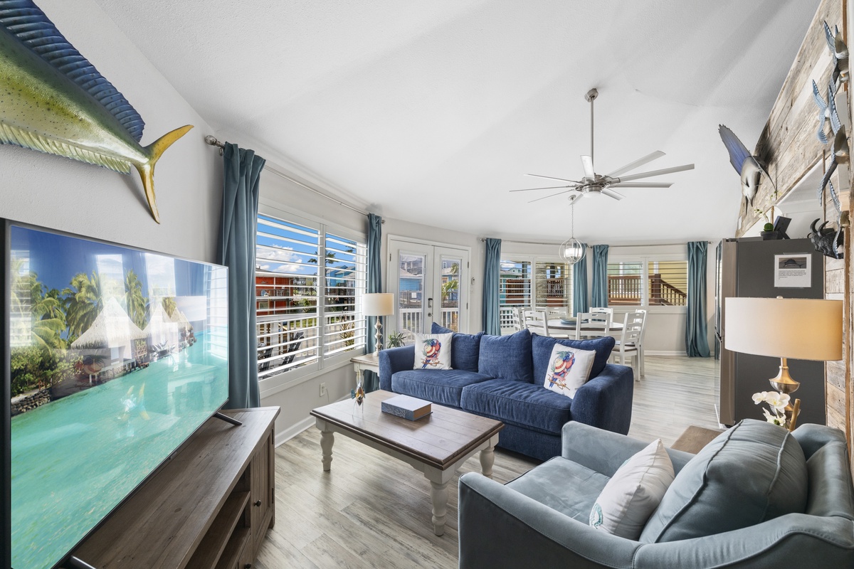 Relax in your coastal living room with plush seating, tropical views on the big screen, and ocean breezes through plantation shutters.