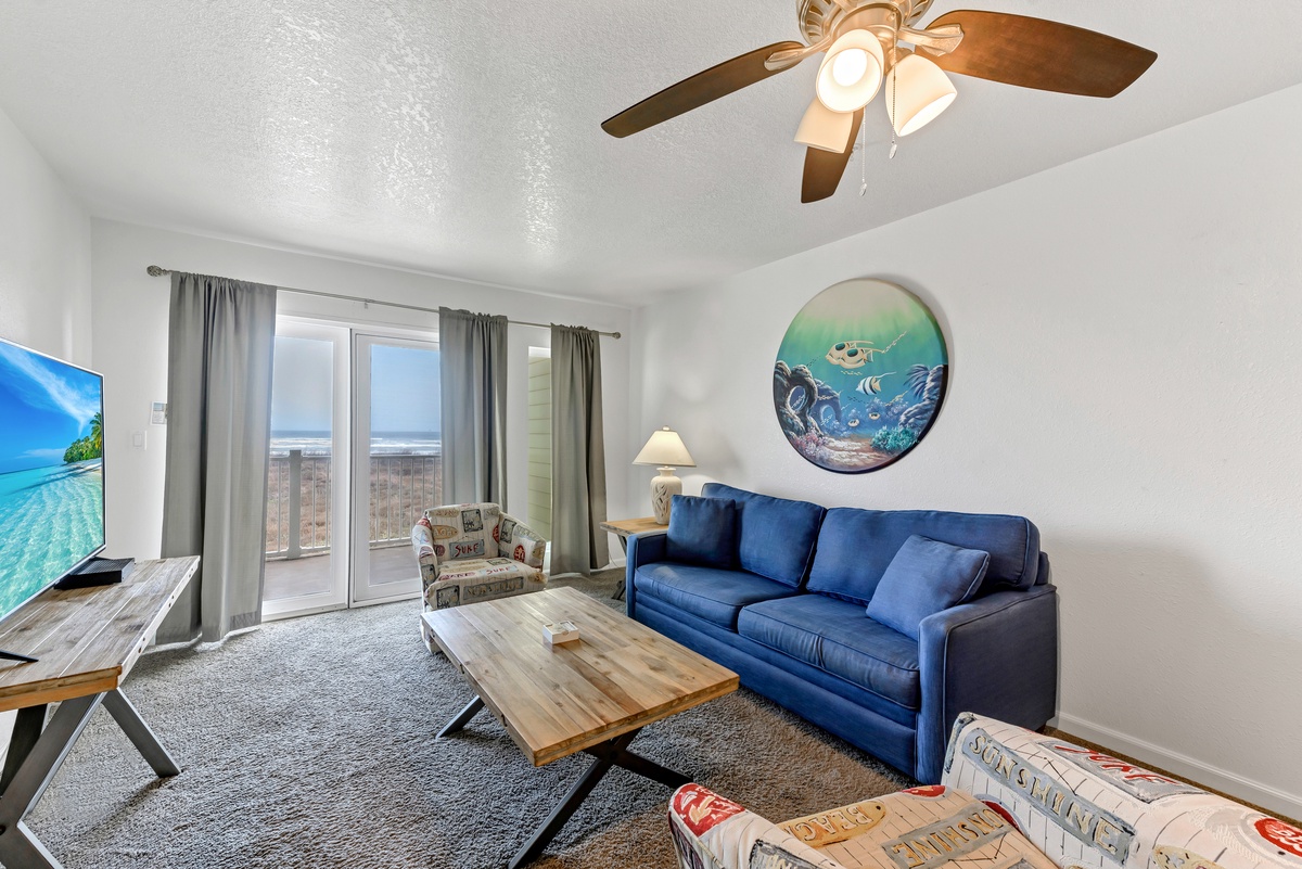 Unwind on your plush blue sofa while enjoying ocean views through sliding doors to your private balcony, with coastal art adding beachy charm.